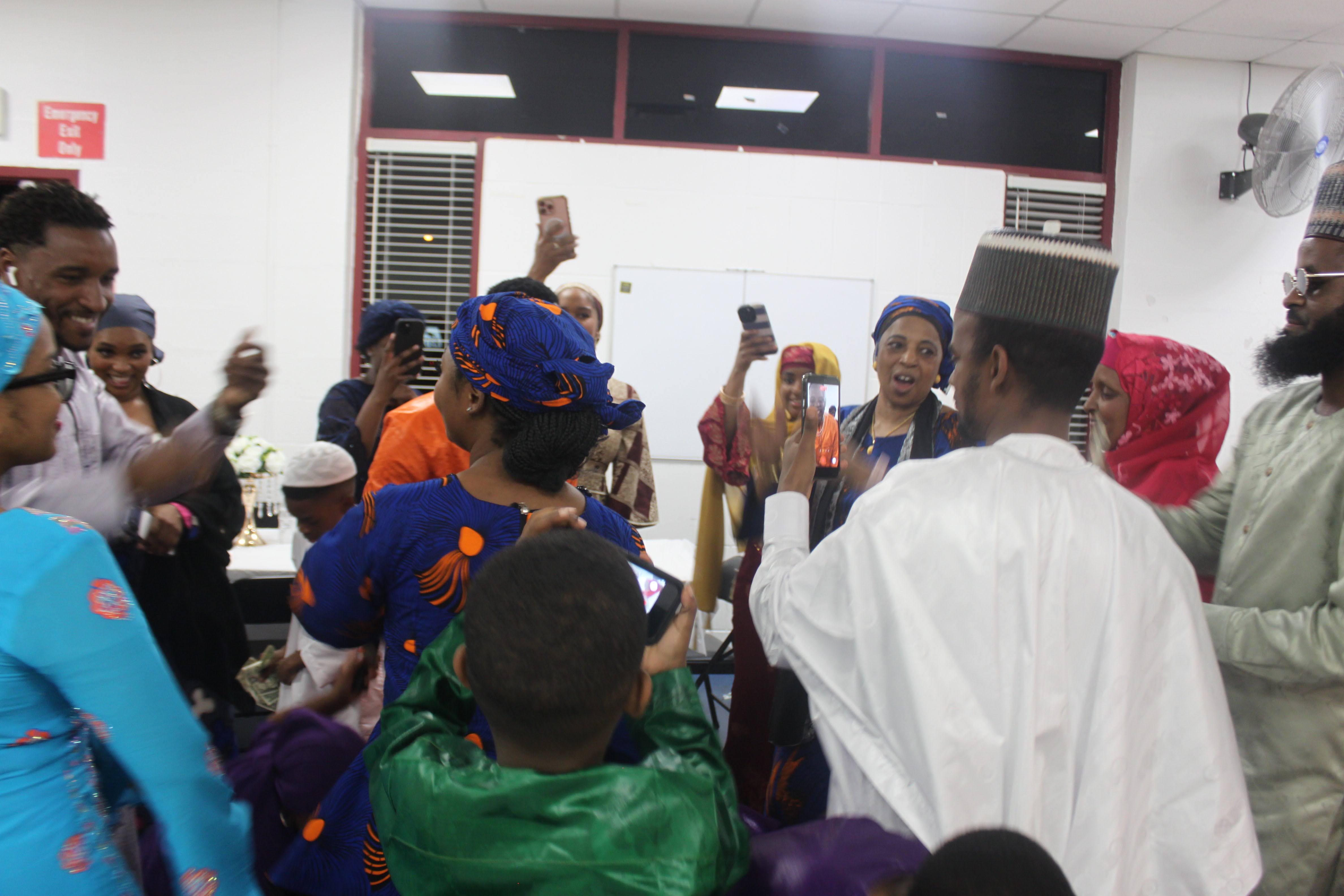 Fulani community members celebrating and filming a joyful moment at the Al Ada dinner